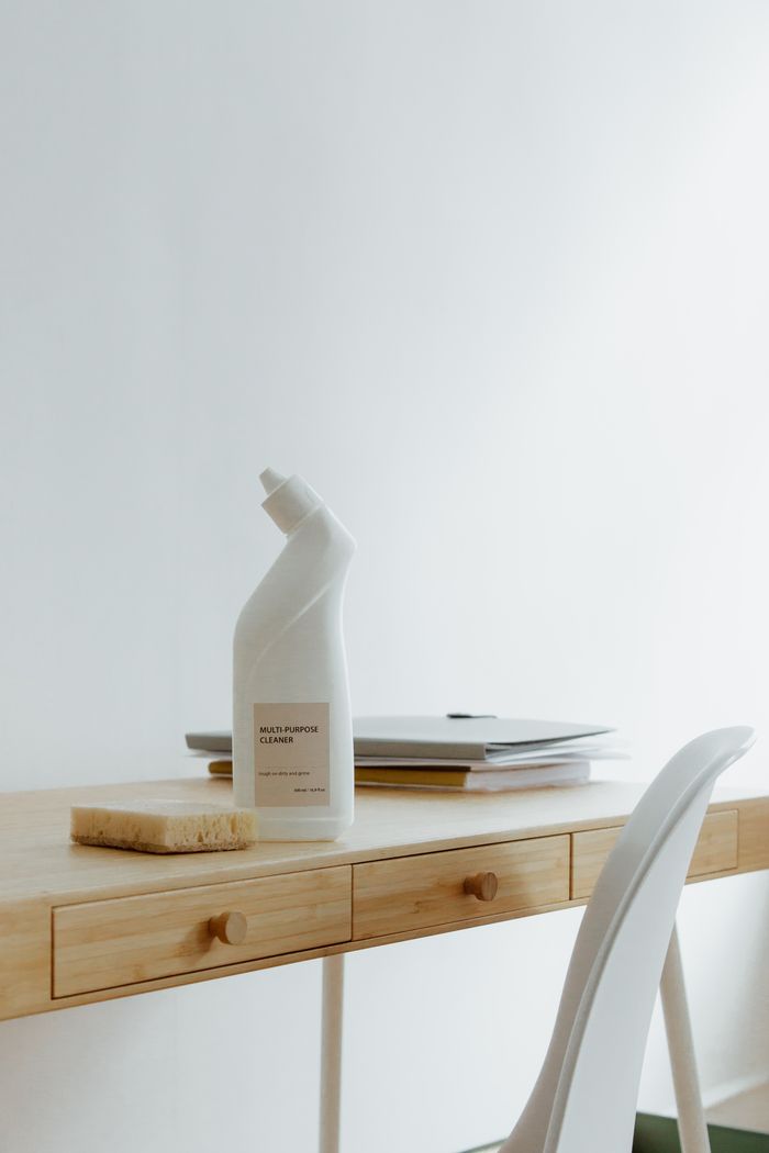 who-we-are A tidy, well-arranged home office desk featuring a cleaning bottle and sponge, highlighting simplicity and practical use.